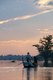 Burma / Myanmar: At sunset a boatman steers tourists close to the U Bein Bridge, the longest teakwood bridge in the world, Taungthaman Lake, near Amarapura, Mandalay